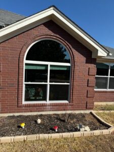 Brick home with large arched geometric window featuring white frame