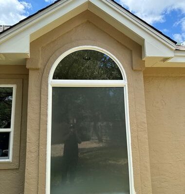 Modern fixed window replacement in arched brick home exterior