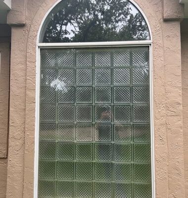 Arched brick home window with outdated glass block before replacement
