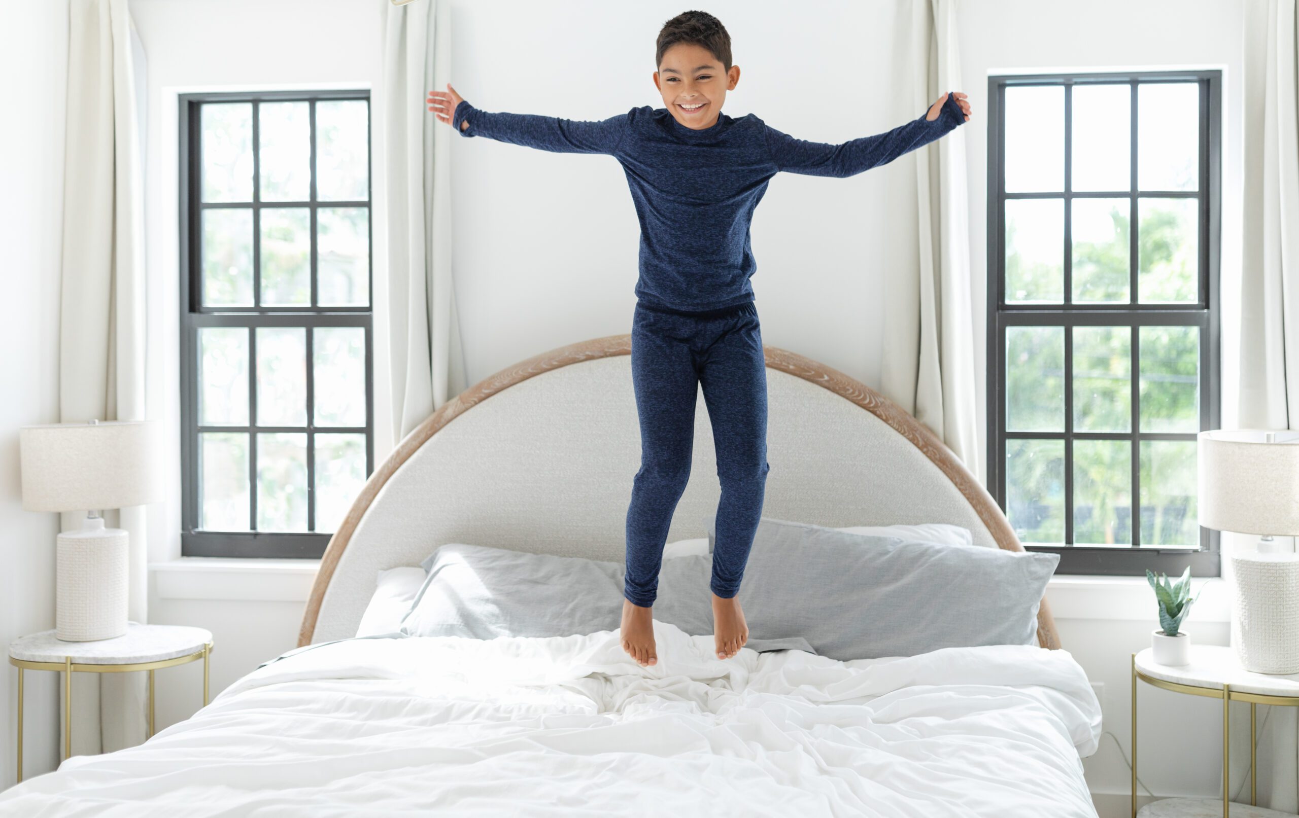 Child jumping on bed in newly completed room with replacement windows